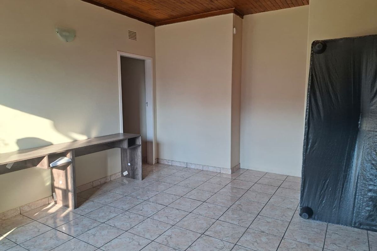 A vacant bedroom featuring tiled flooring, a timber-paneled ceiling, and a built-in desk unit.