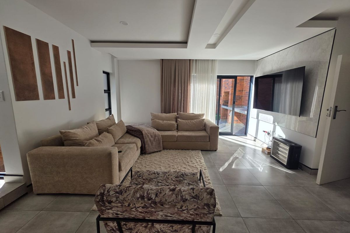 Modern living room featuring large format floor tiles, a recessed ceiling with integrated lighting, and direct access to an outdoor patio area.