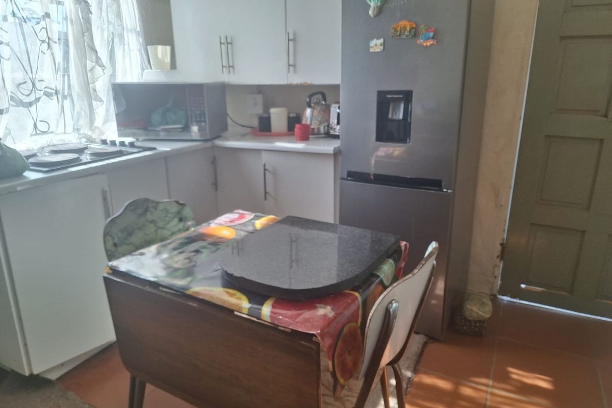 A compact kitchen featuring built-in cabinetry, laminate countertops, and a built-in hob, with tiled flooring throughout.