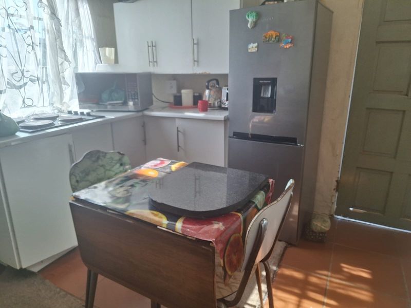 A compact kitchen featuring built-in cabinetry, laminate countertops, and a built-in hob, with tiled flooring throughout.