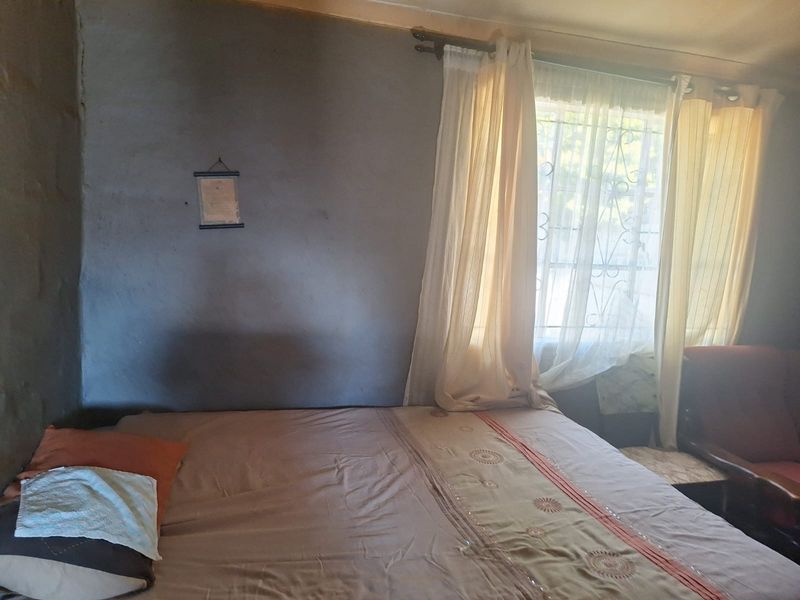 A bedroom featuring a window with security bars and basic wall finishes, requiring cosmetic updates to improve the overall aesthetic.
