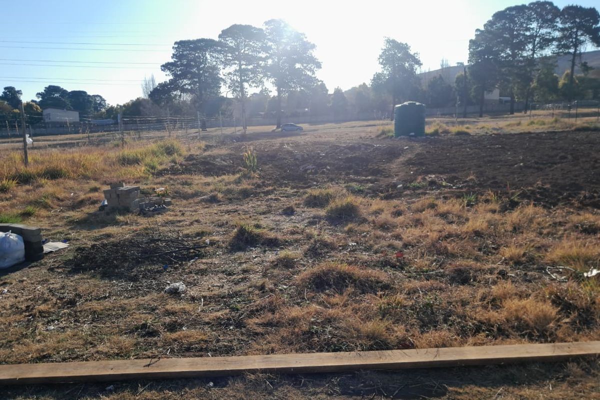 A view of a vacant residential plot featuring a water storage tank and perimeter wire fencing.