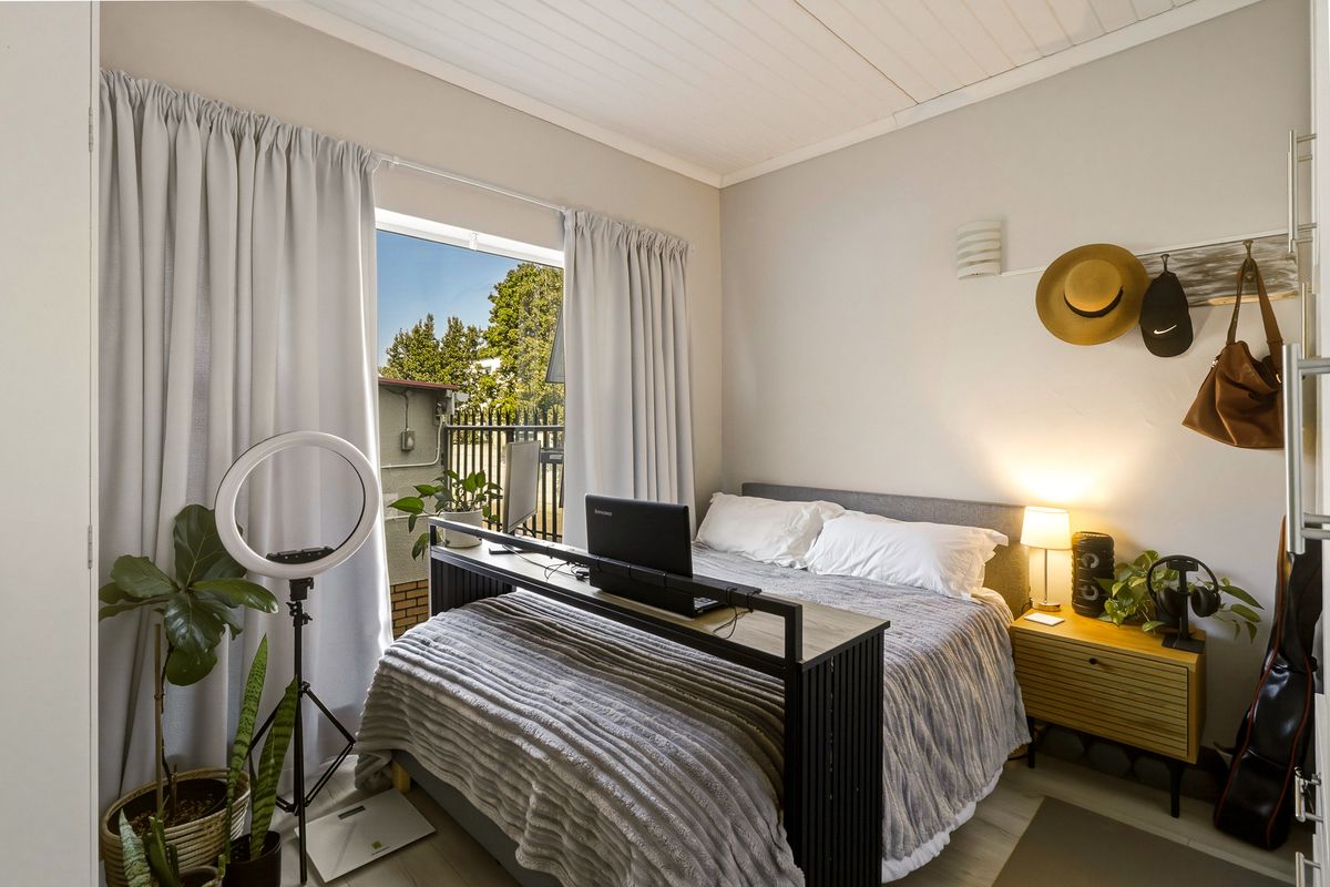 A well-lit bedroom featuring timber-look flooring, a tongue and groove ceiling, and a sliding glass door providing access to the exterior.