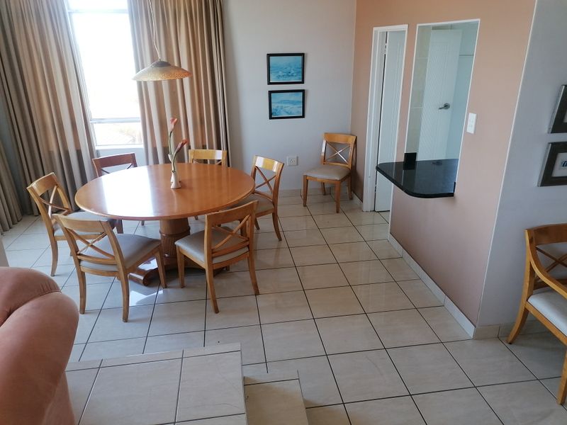A dining area featuring tiled flooring and a convenient pass-through window with a granite breakfast bar connecting to the adjacent kitchen space.