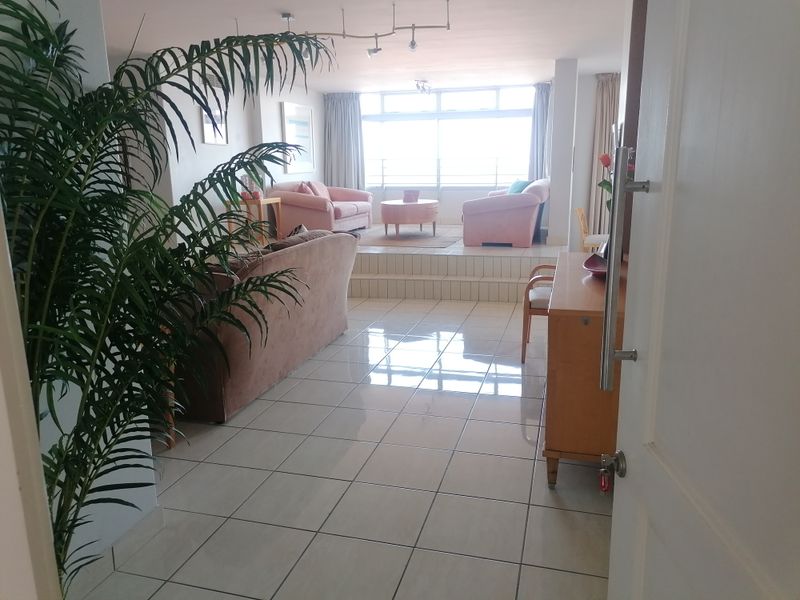 Spacious living area featuring tiled flooring, a raised platform seating area, and large windows providing natural light.