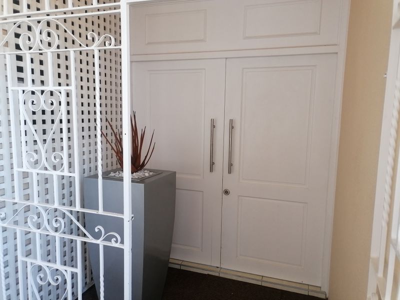 A secure apartment entrance featuring white double doors and a decorative white metal security gate.