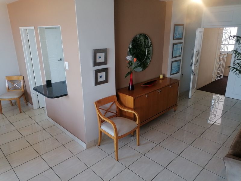 An inviting entrance area featuring light-colored floor tiles, a granite breakfast bar pass-through, and a secure entrance door with a security gate.