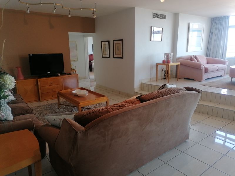 Spacious open-plan living area featuring tiled flooring, a split-level layout, and integrated ducted air conditioning, offering a versatile space for relaxation.