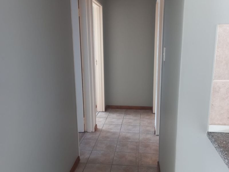 A clean and well-maintained interior hallway featuring neutral wall tones and tiled flooring, providing access to multiple rooms within the townhouse.