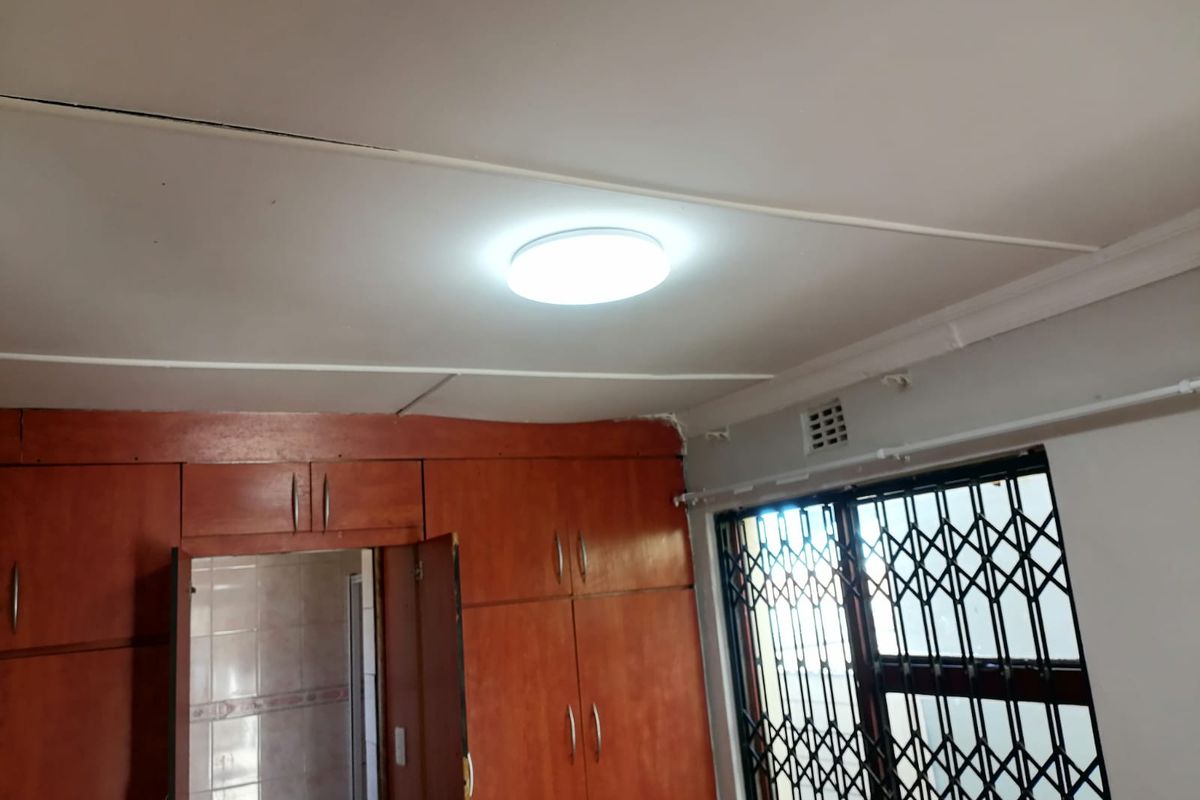 Bedroom featuring built-in wooden cupboards, security gate on the window, and standard ceiling finishes.