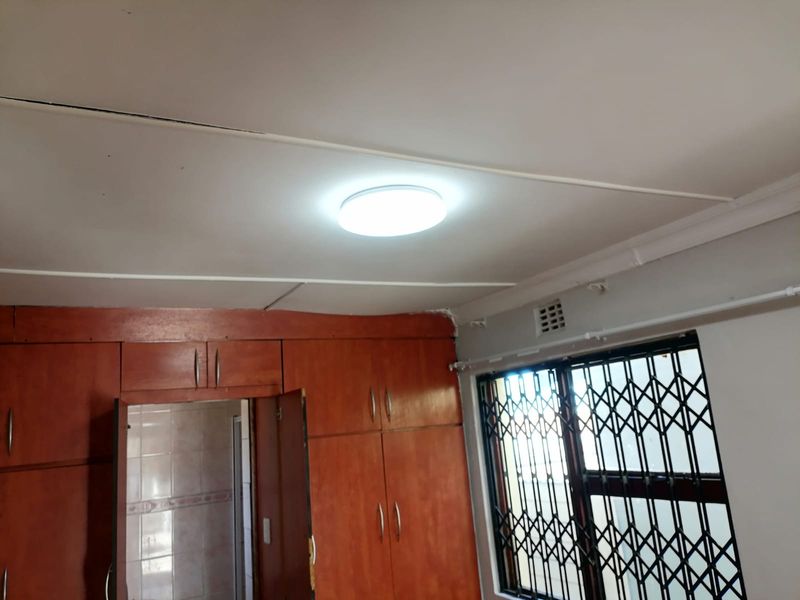 Bedroom featuring built-in wooden cupboards, security gate on the window, and standard ceiling finishes.