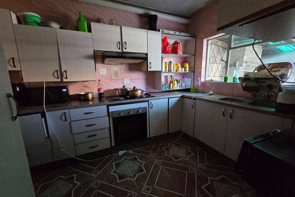 A functional kitchen featuring built-in cabinetry, an integrated oven and hob, and a tiled backsplash, offering potential for a modern renovation.