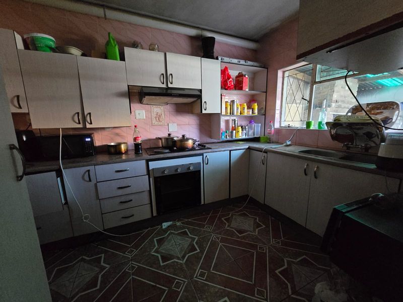 A functional kitchen featuring built-in cabinetry, an integrated oven and hob, and a tiled backsplash, offering potential for a modern renovation.