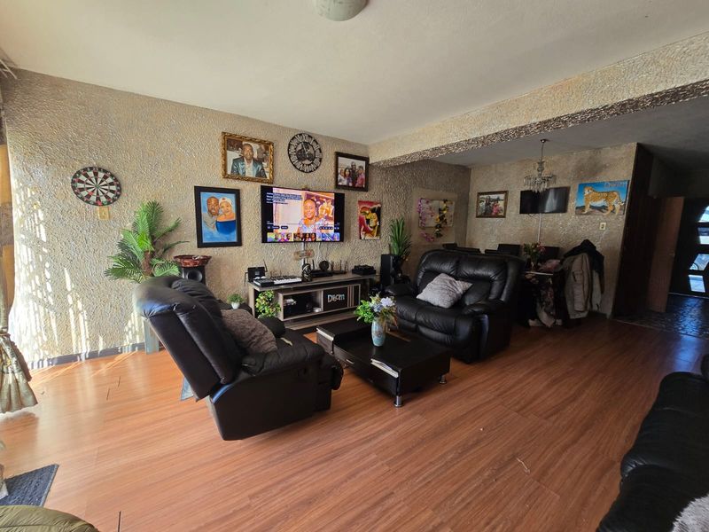 A spacious living room featuring laminate flooring and textured wall finishes, providing a functional and comfortable living area.