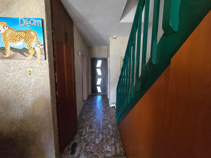 Entrance hallway featuring a staircase with a green railing, built-in storage, and textured wall finishes leading to the front door.