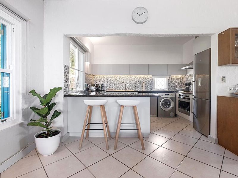 Modern kitchen featuring a mosaic tile backsplash, granite countertops, built-in oven, extractor fan, and integrated cabinetry with tiled flooring.