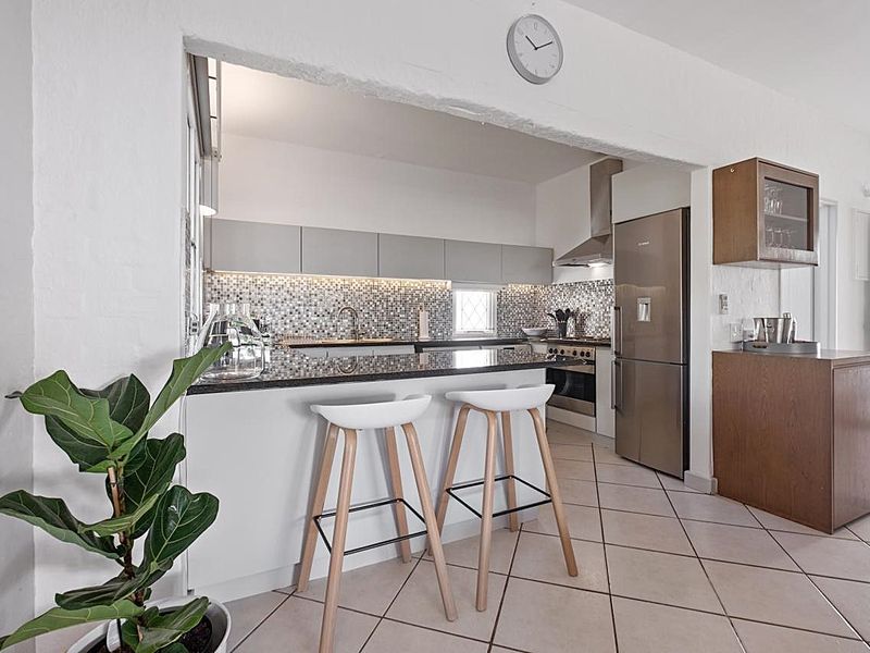 Modern kitchen featuring granite countertops, mosaic tile backsplash, stainless steel appliances, and ample built-in cabinetry with a convenient breakfast bar pass-through.