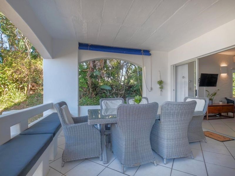 A covered patio featuring tiled flooring, built-in bench seating, and sliding glass doors providing seamless access to the interior living space.