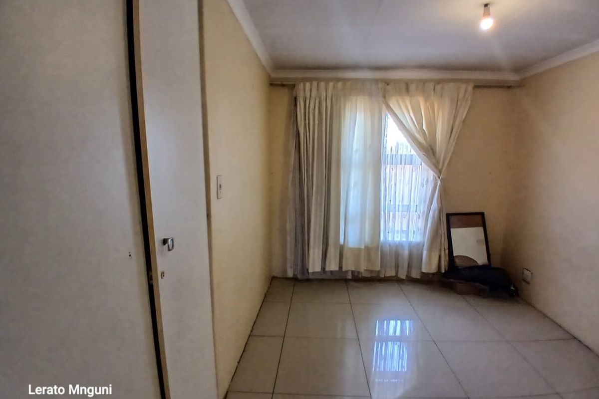 A vacant bedroom featuring tiled flooring and a built-in cupboard, offering a blank canvas for personalization.