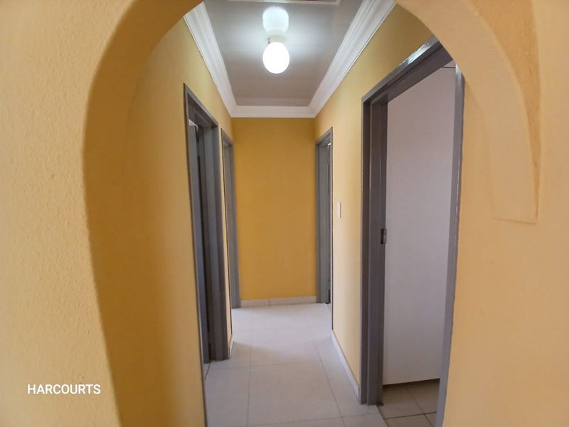 A bright hallway featuring an arched entrance, tiled flooring, and neutral yellow walls, providing access to multiple rooms.