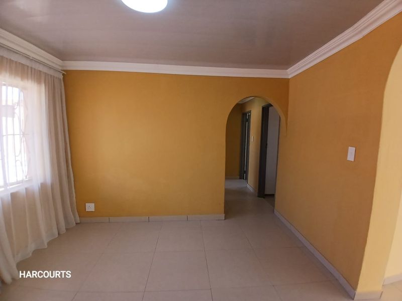 A bright, empty living room featuring tiled flooring, a decorative archway, and classic cornice detailing, providing a clean canvas for personalization.