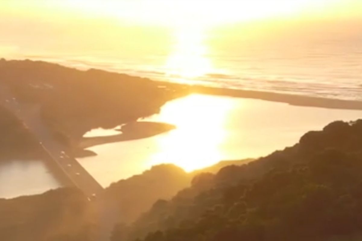 A scenic elevated view of the coastline, river mouth, and bridge at sunset, showcasing the natural landscape surrounding the property.