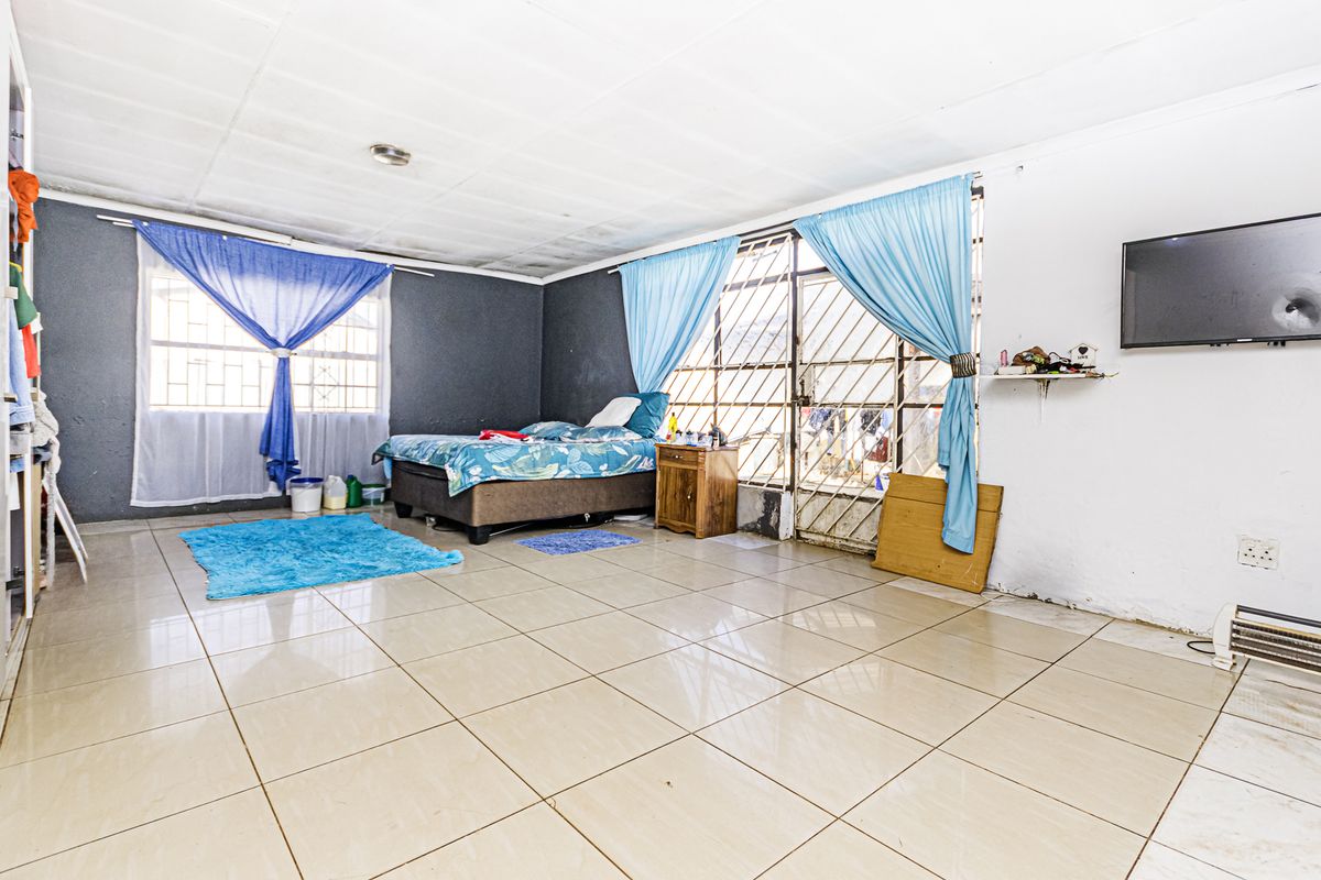 Spacious bedroom featuring tiled flooring, security gate access, and built-in storage, offering a functional layout with potential for cosmetic updates.