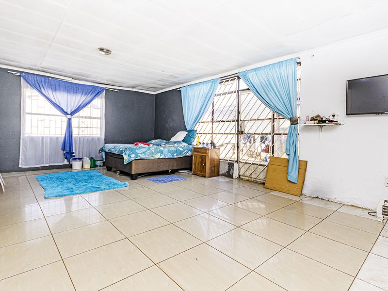 Spacious bedroom featuring tiled flooring, security gate access, and built-in storage, offering a functional layout with potential for cosmetic updates.