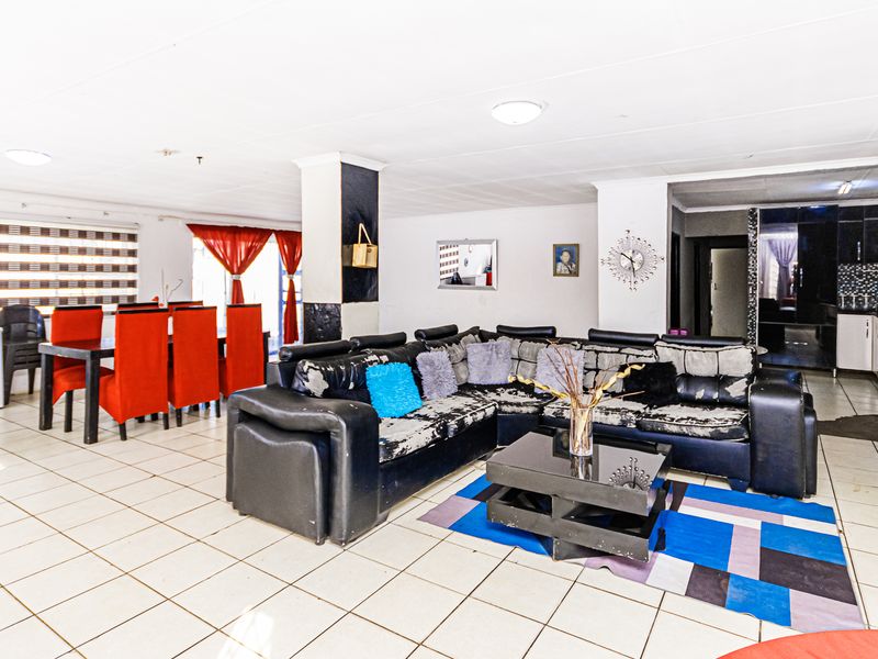 Spacious open-plan living and dining area featuring tiled flooring and structural columns, offering a versatile layout for family living.