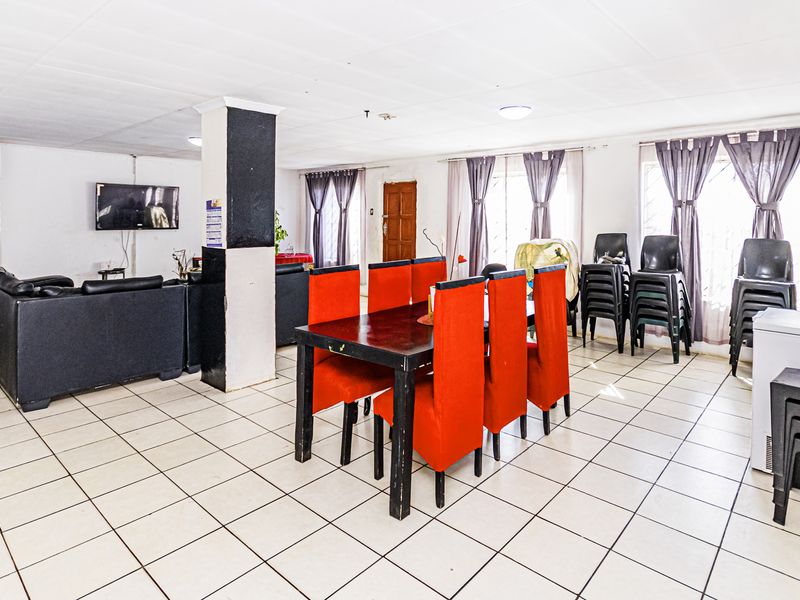 Spacious open-plan living and dining area featuring ceramic tiled flooring and a central structural column, offering a versatile layout for family living.
