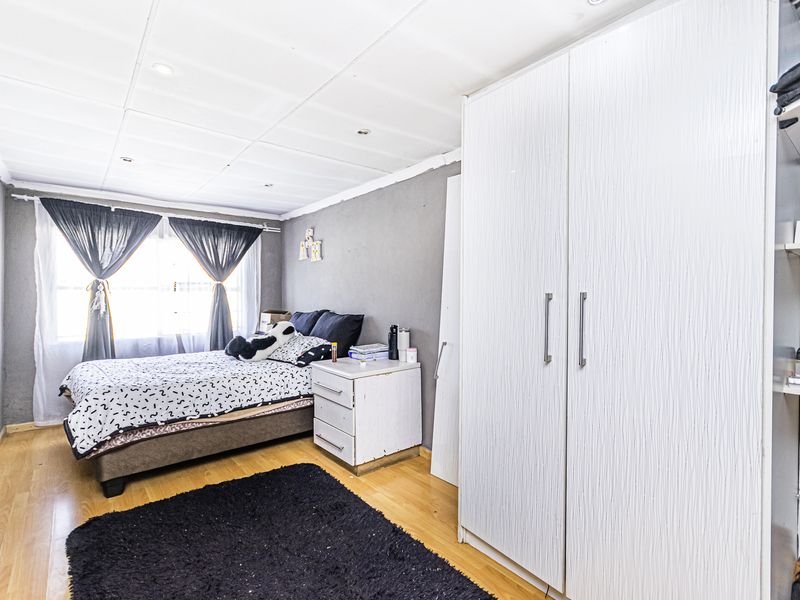 A bedroom featuring laminate flooring, a large built-in wardrobe, and recessed ceiling lighting.