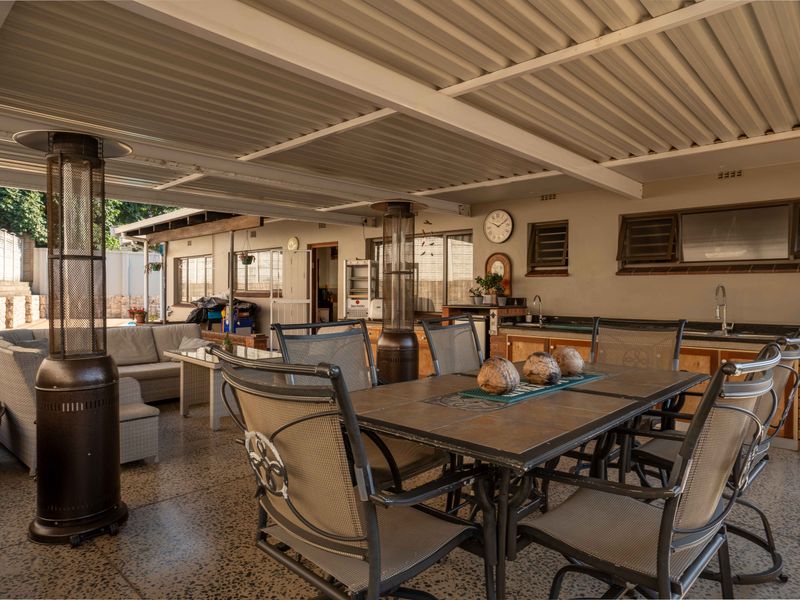 Spacious covered patio featuring a built-in brick braai, outdoor sink, and durable terrazzo flooring, ideal for outdoor entertaining.