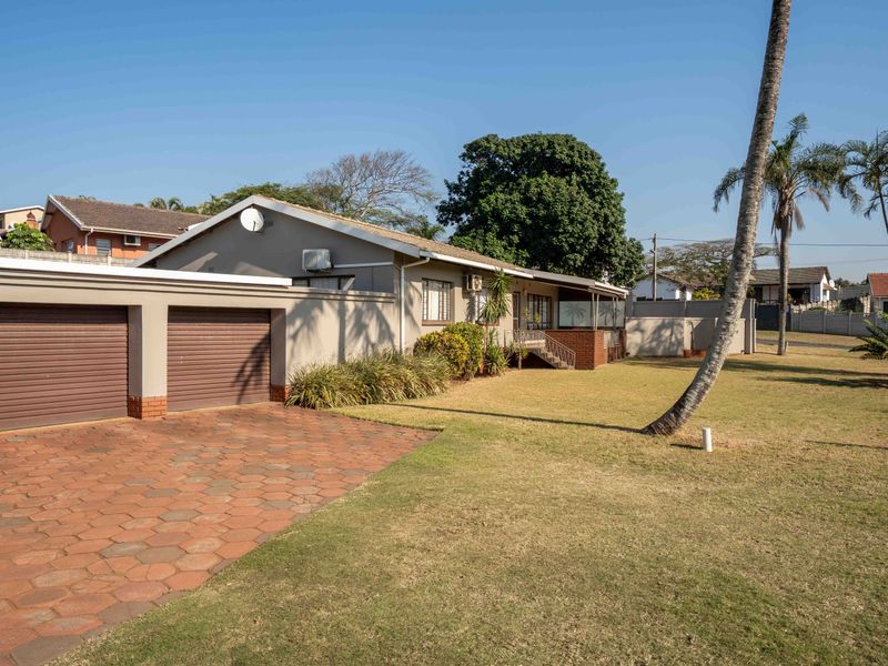 Front view of the property featuring a double garage, paved driveway, and a well-maintained lawn area.