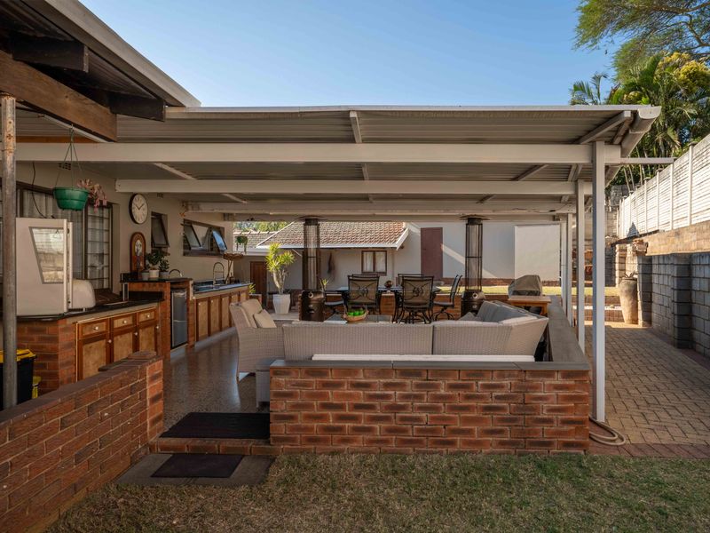 Spacious covered outdoor patio featuring a built-in brick kitchenette with sink, ideal for alfresco dining and entertaining in a private garden setting.