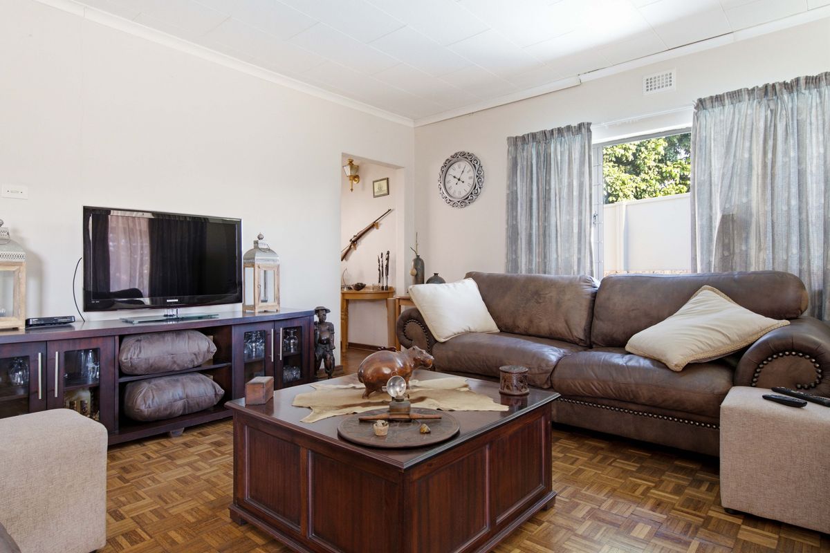 A comfortable living room featuring classic parquet flooring and a coved ceiling, providing a warm and inviting space for relaxation.