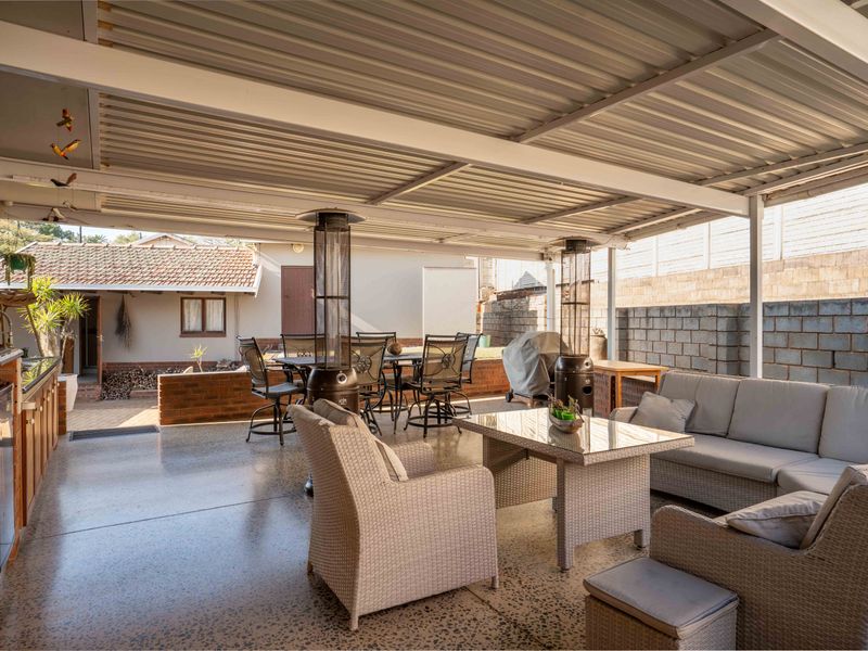 Spacious covered patio featuring a corrugated metal roof, polished concrete flooring, and built-in outdoor cabinetry, ideal for alfresco dining and entertaining.