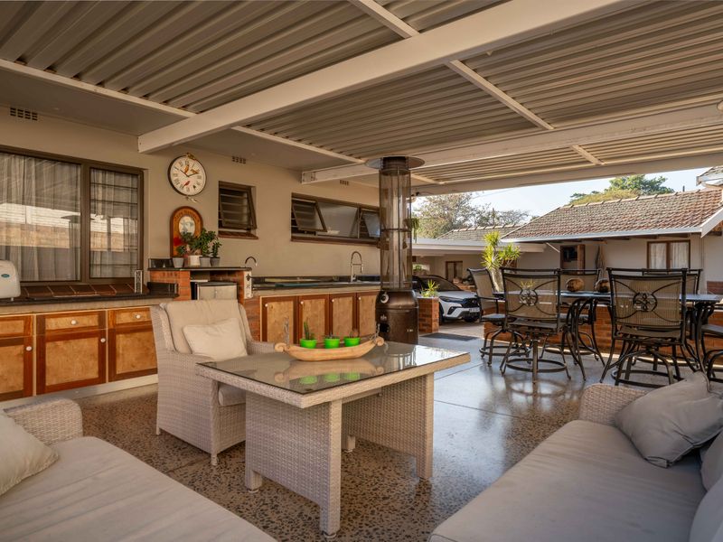 Spacious covered patio featuring built-in cabinetry, stone countertops, and a sink, ideal for outdoor entertaining and dining.