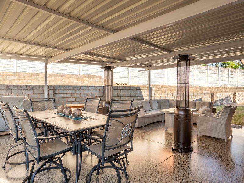 A spacious covered patio area featuring an exposed aggregate floor and a corrugated metal roof, enclosed by a perimeter cinder block wall.