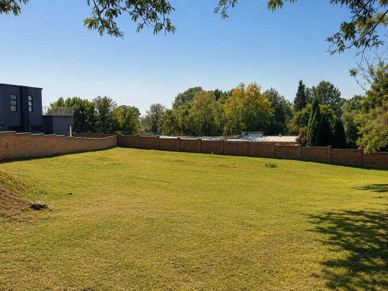 A spacious, well-maintained residential garden featuring a manicured lawn and a secure brick boundary wall.