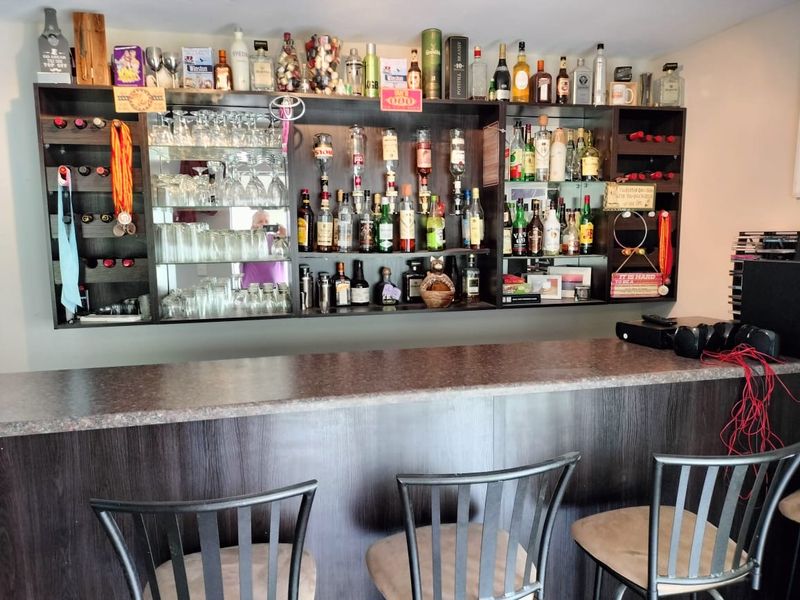 A dedicated home bar area featuring a built-in counter and extensive integrated shelving with mirrored backing for display.