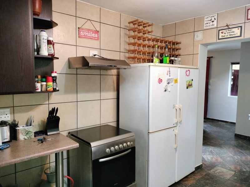 A functional kitchen area featuring tiled splashbacks, a stainless steel extractor fan, a freestanding oven, and built-in shelving units.