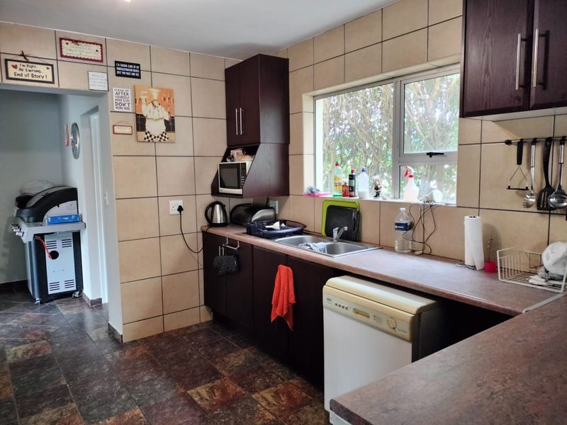 A functional kitchen featuring dark wood cabinetry, laminate countertops, tiled splashbacks, and tiled flooring, offering a practical layout with ample storage space.