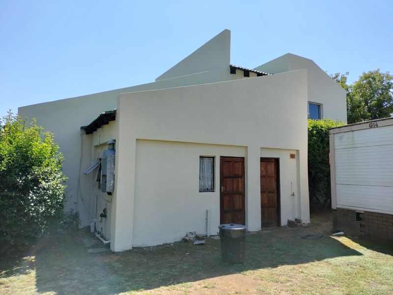 Rear exterior view of the property showing the building facade, timber access doors, and external utility fixtures.
