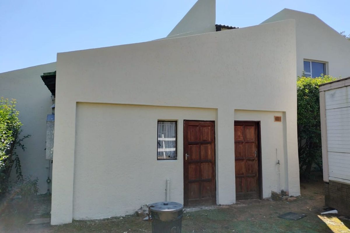 Rear exterior view of the property featuring a rendered facade with two timber panel doors and an external water tap.