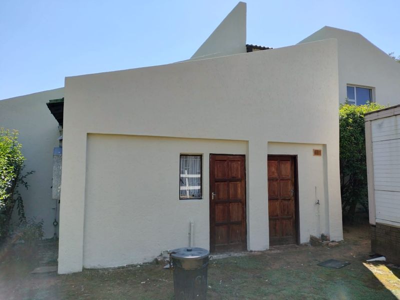 Rear exterior view of the property featuring a rendered facade with two timber panel doors and an external water tap.