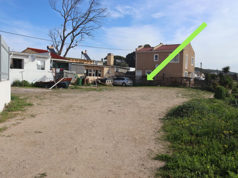 A view of a vacant residential plot featuring unpaved ground and perimeter fencing, situated in a developed neighborhood setting.
