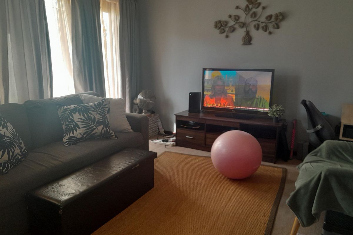 A comfortable living room area featuring large windows with curtains, providing natural light and a functional space for relaxation.