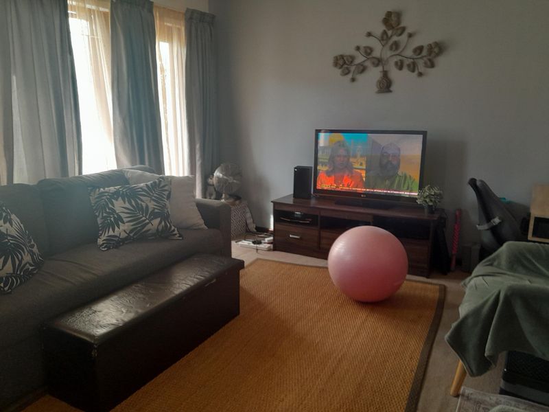 A comfortable living room area featuring large windows with curtains, providing natural light and a functional space for relaxation.