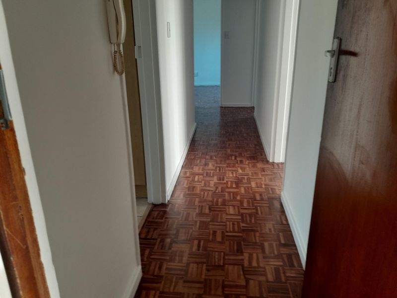 A functional hallway featuring classic parquet flooring and an integrated intercom system, providing access to various rooms within the apartment.