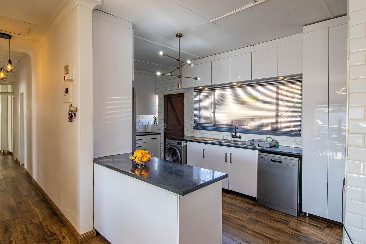 Modern kitchen featuring white cabinetry, subway tile backsplash, dark stone countertops, and integrated appliances, seamlessly flowing into the adjacent hallway.